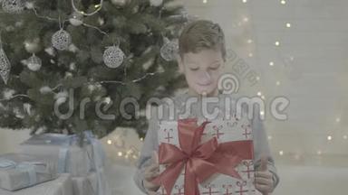 <strong>喜洋洋</strong>的孩子兴奋的男孩打开圣诞礼物盒惊讶地坐在新年树附近